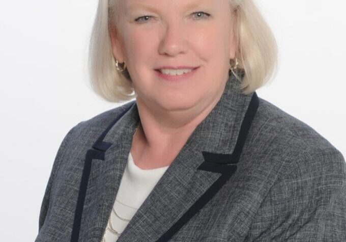 A woman in a gray suit smiling for the camera.