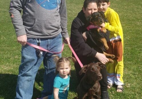 A family with a dog on a leash in a park.