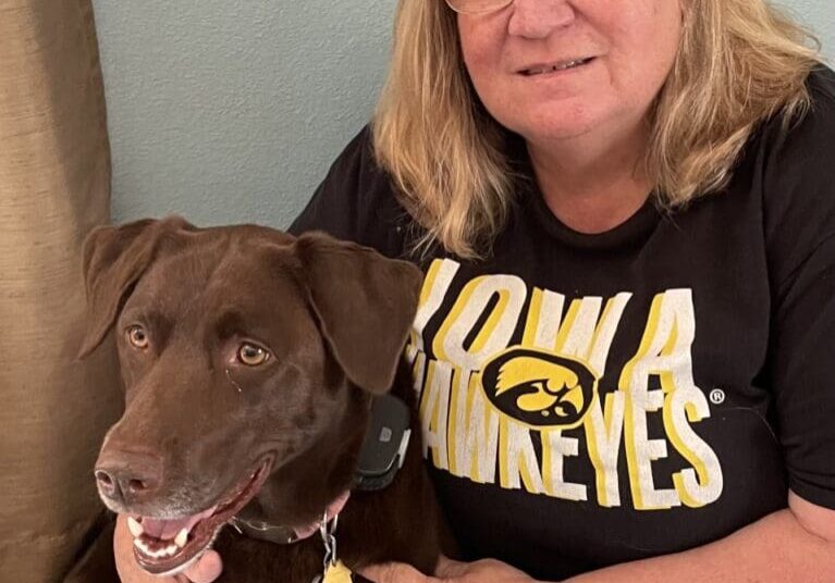 Woman in Iowa Hawkeyes shirt with brown dog.