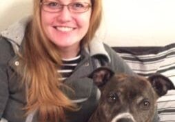 A woman sitting on a bed with her dog.