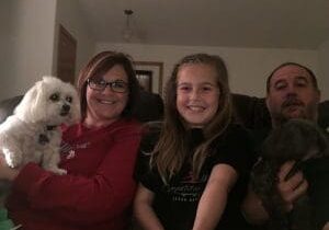 A family sitting on a couch with two dogs.