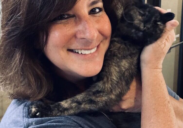 A woman holding a black cat in her arms.