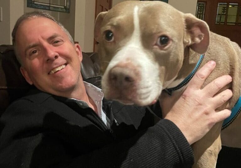 A man sitting on a couch with a dog.