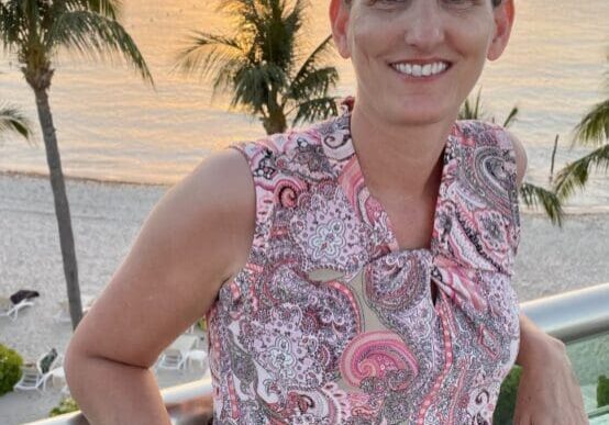 A woman standing on a balcony overlooking the ocean.