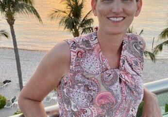 A woman standing on a balcony overlooking the ocean.