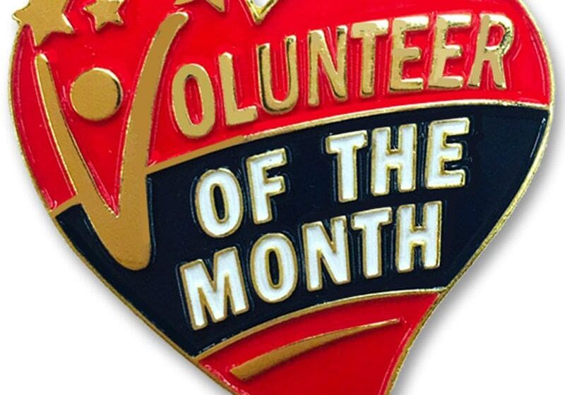 A heart shaped badge with the words volunteer of the month.