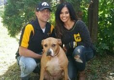 A man and woman posing for a picture with their dog.