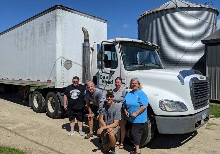 A group of people posing in front of a semi truck.